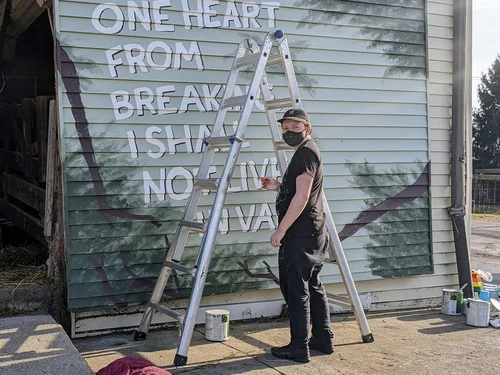 Me, the artist, looking over my shoulder as I paint the robin mural in a candid shot.